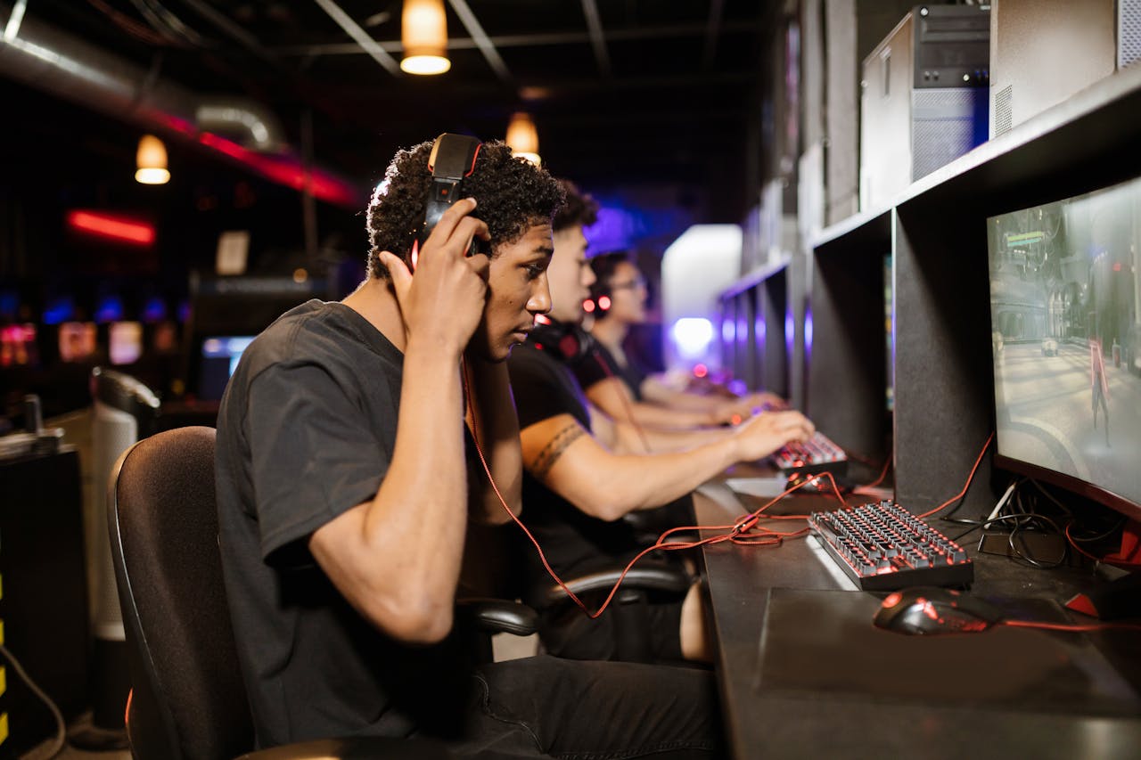 A group of young adults intensely focused on playing video games in a modern gaming lounge.